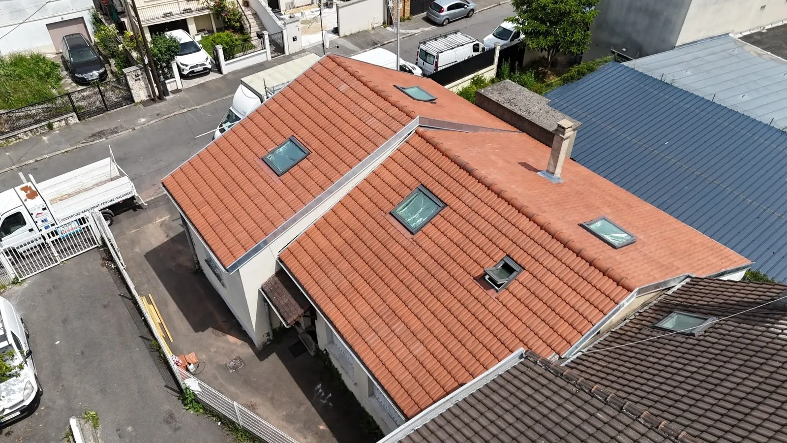 Vue aérienne de toitures en tuiles orangées comportant plusieurs fenêtres de toit
